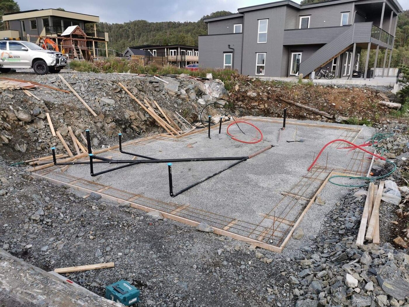 Byggegrop sprengt og gravd ut av fast fjell, klargjort med bunnledninger og armering før støp
