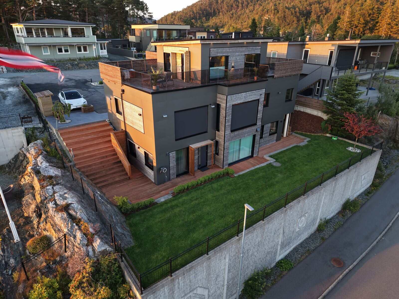 Dronefoto av funkiseneboligen på Nordstrøno i kveldslys, med takterrasse og opparbeidet hage