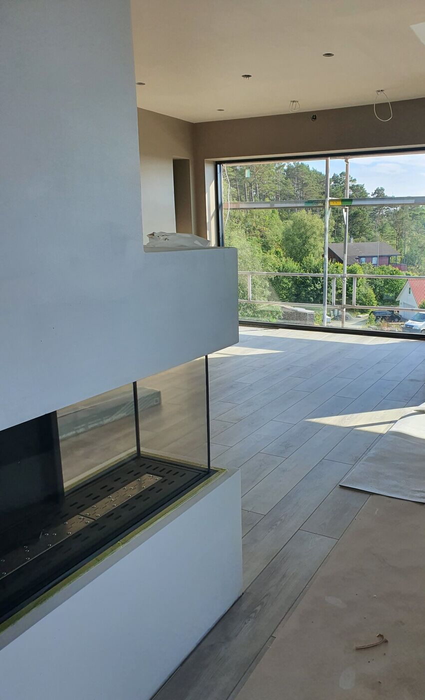 Innebygd gasspeis med glassfront i stuen, ved siden av store glassdører ut mot takterrassen og sjøutsikten