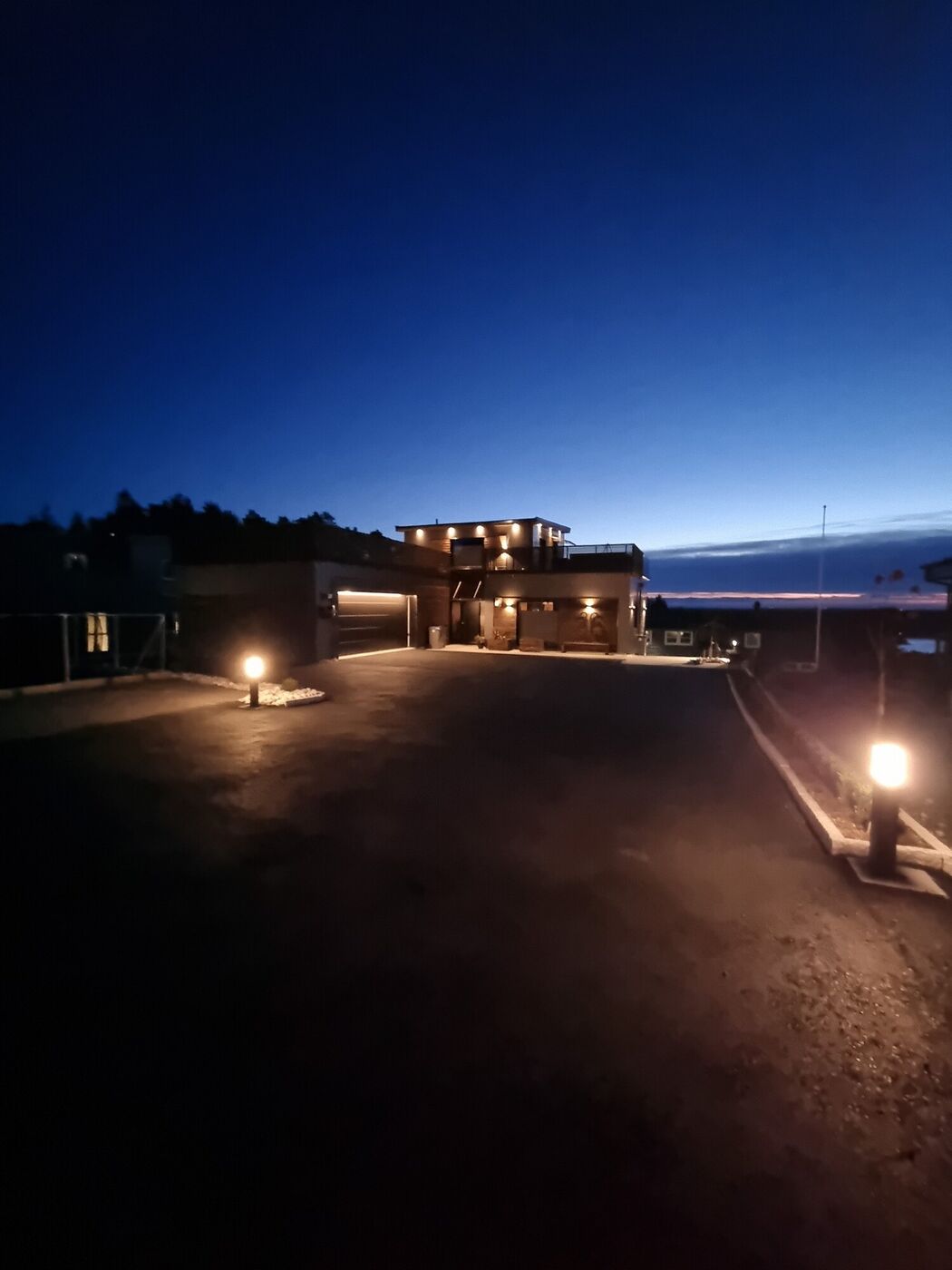 Takterrasse i blåtimen med opplyst rekkverk og sjøutsikt